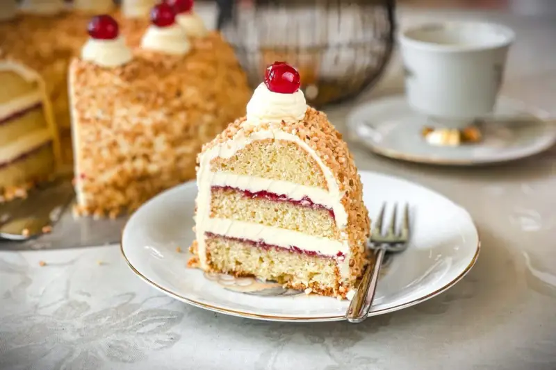 Ein Stück Frankfurter Kranz mit Buttercreme, Marmelade und Nüssen, garniert mit einer Kirsche. Ein Genuss für jeden Kaffeetisch.